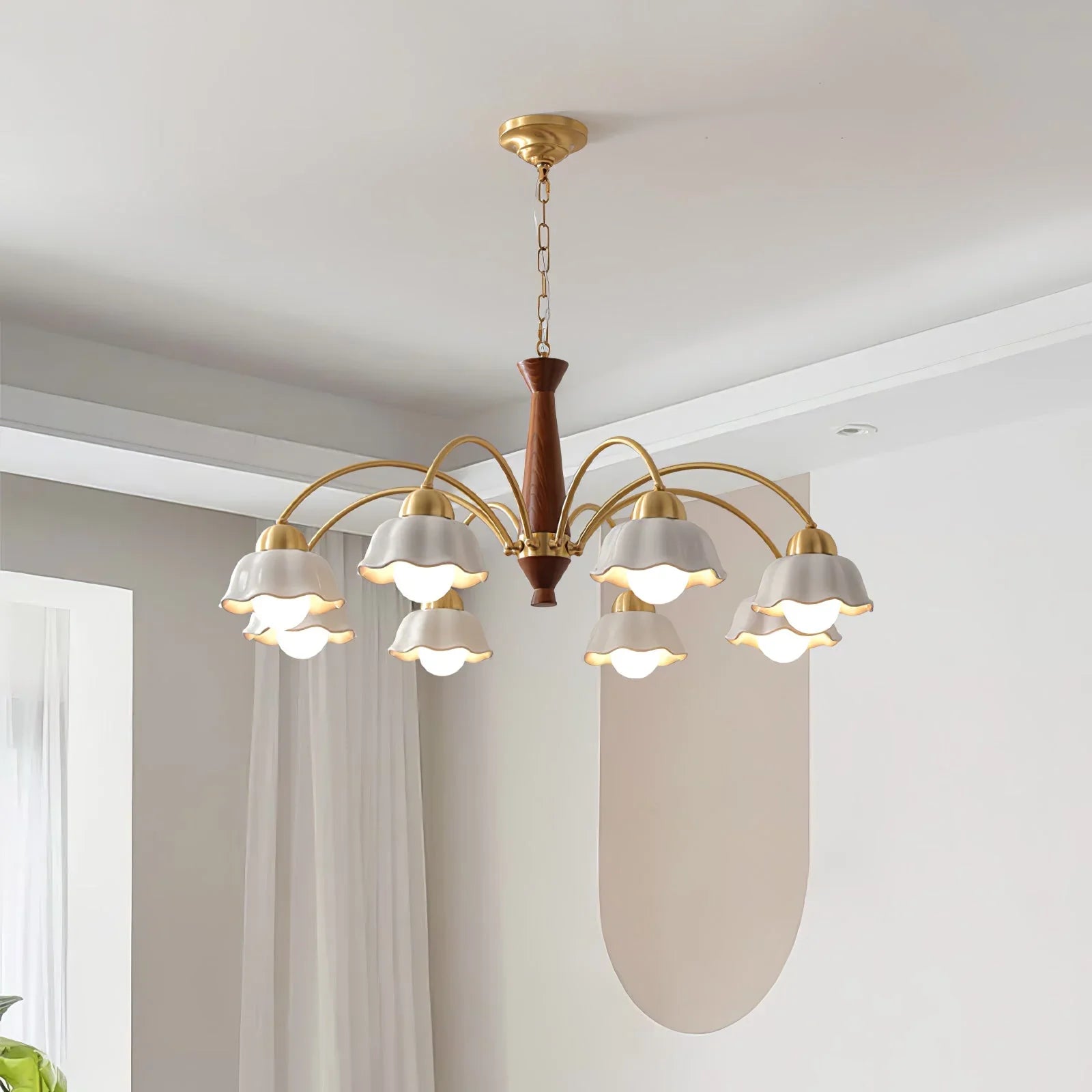 Modern brass chandelier with walnut wood center and eight white flower-shaped lampshades in bright room