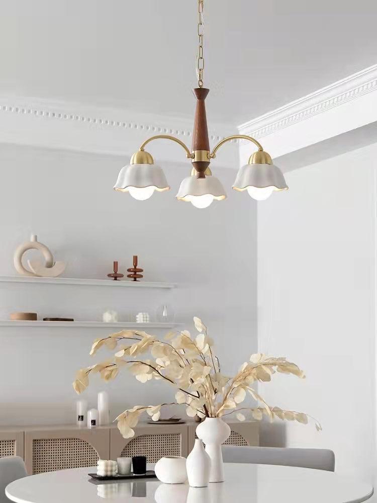 Modern 3-head brass and walnut wood pendant chandelier with white flower-shaped shades in minimalist dining room