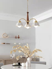 Modern 3-head brass and walnut wood pendant chandelier with white flower-shaped shades in minimalist dining room