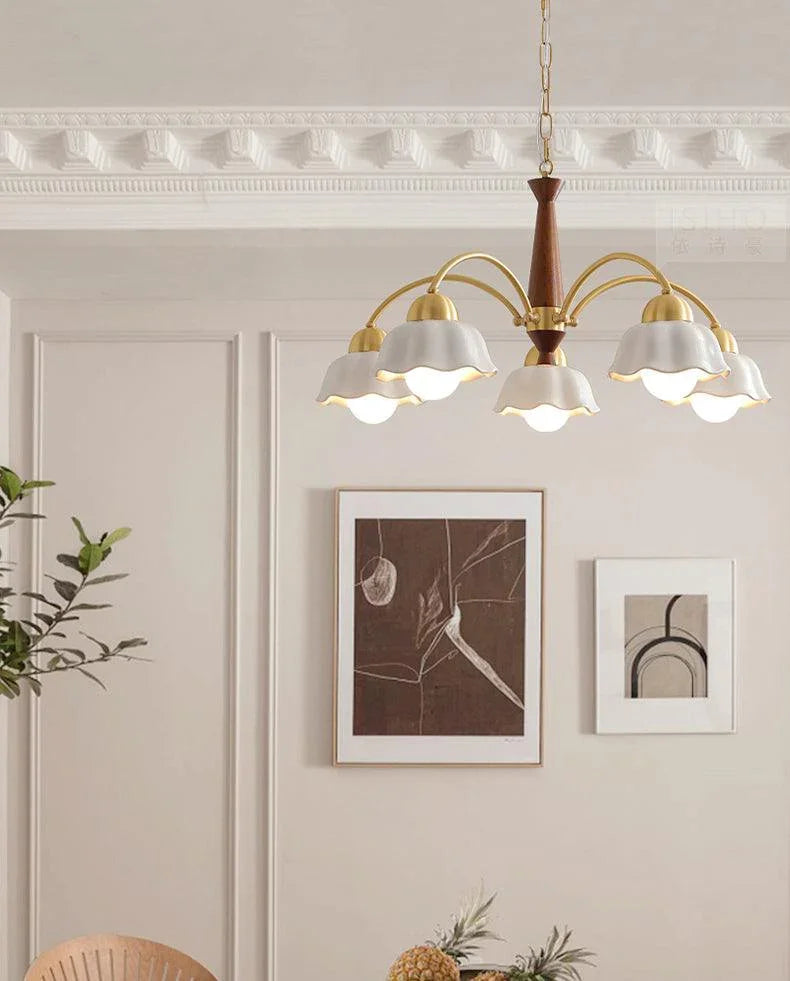 Modern brass and walnut wood chandelier with six petal-shaped white shades in a minimalist living room