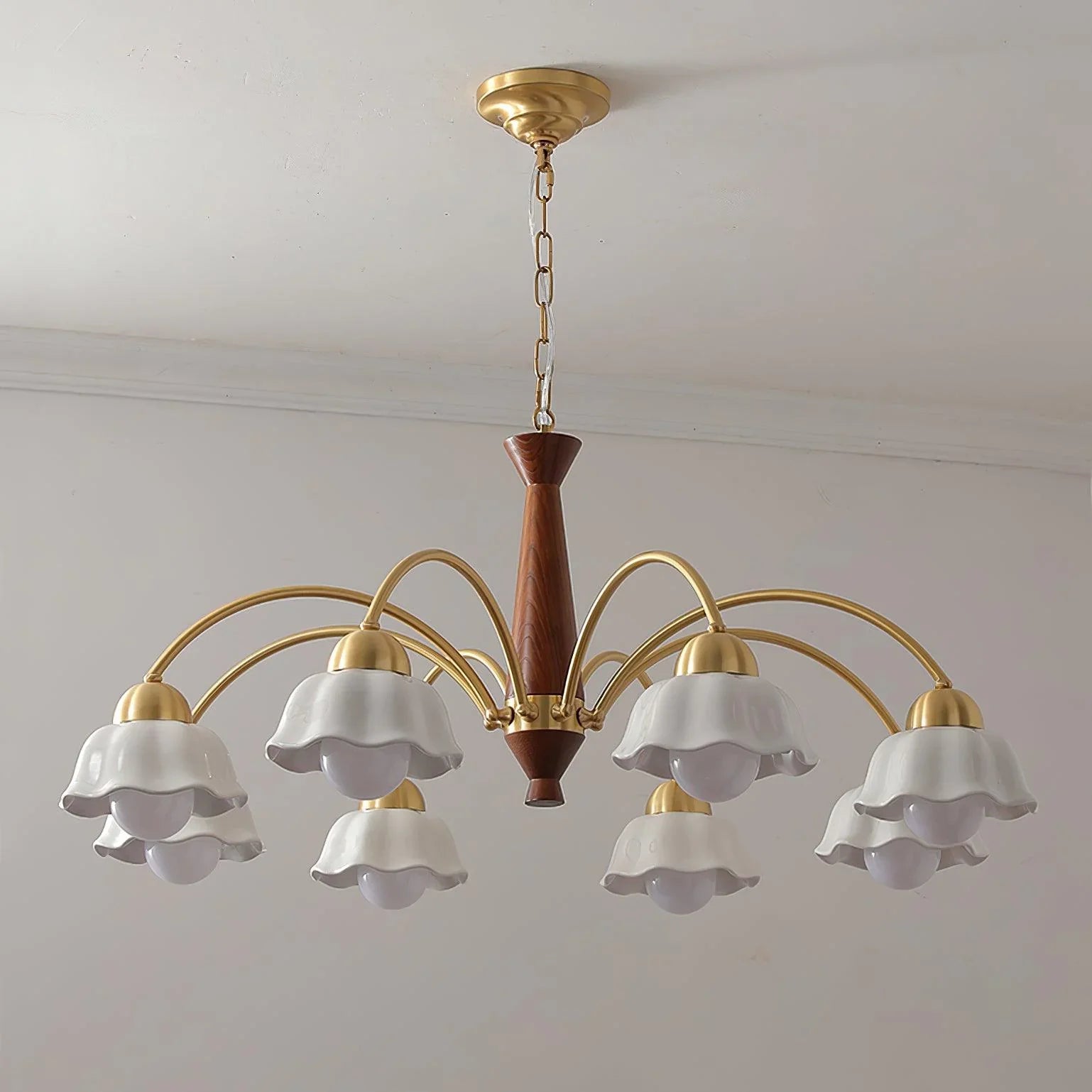 Modern chandelier pendant lamp with brass arms and white flower-shaped shades on walnut wood center