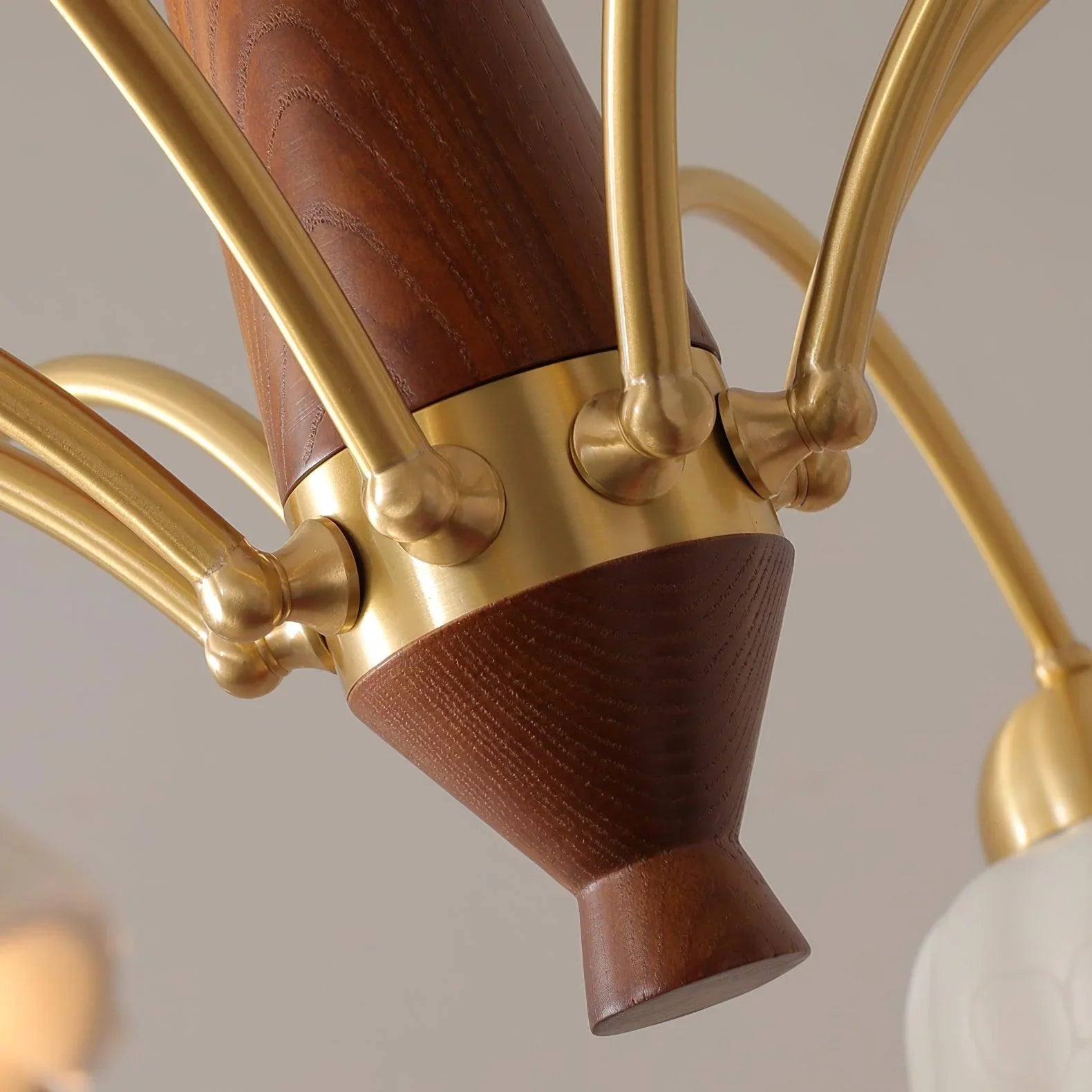 Close-up of YH Lamps modern chandelier in brass and walnut wood with curved arms and detailed craftsmanship