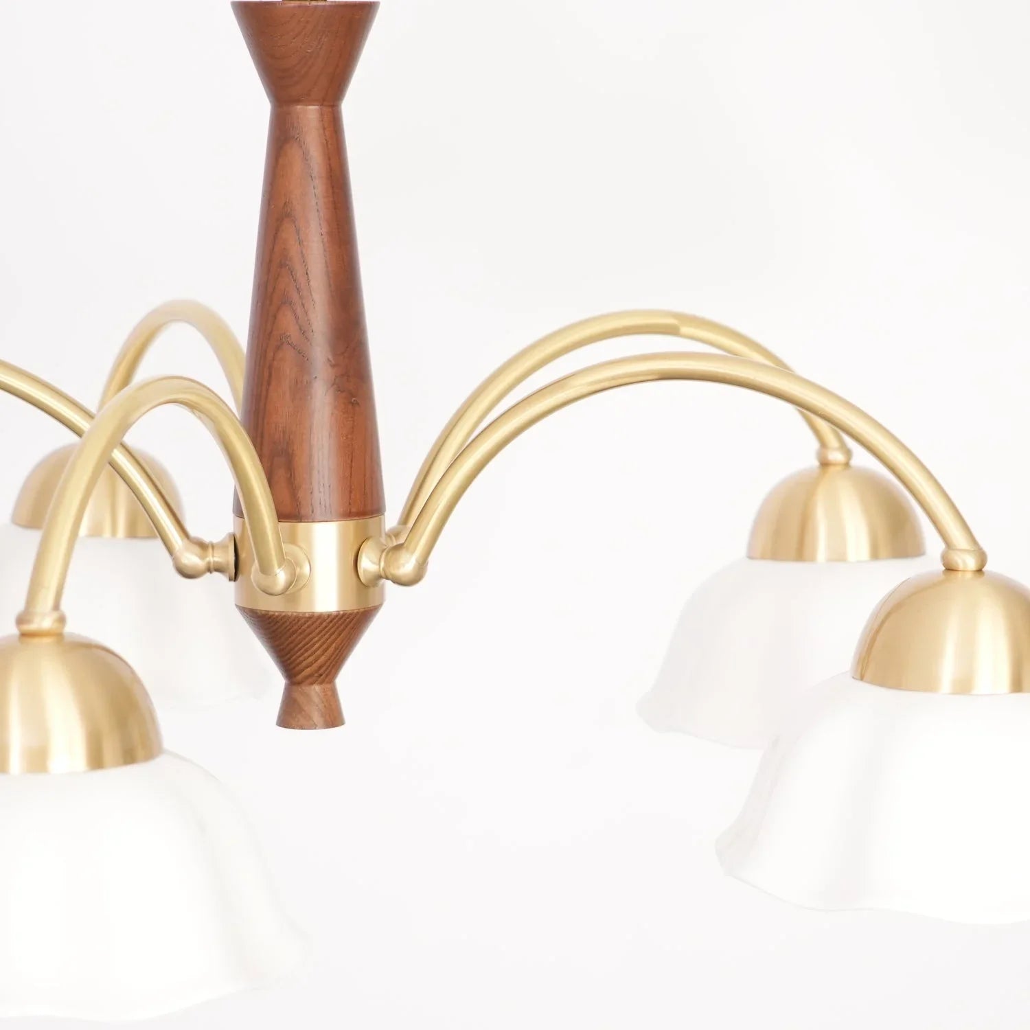 Modern chandelier with three brass arms, white glass bell-shaped shades, and walnut wood centerpiece