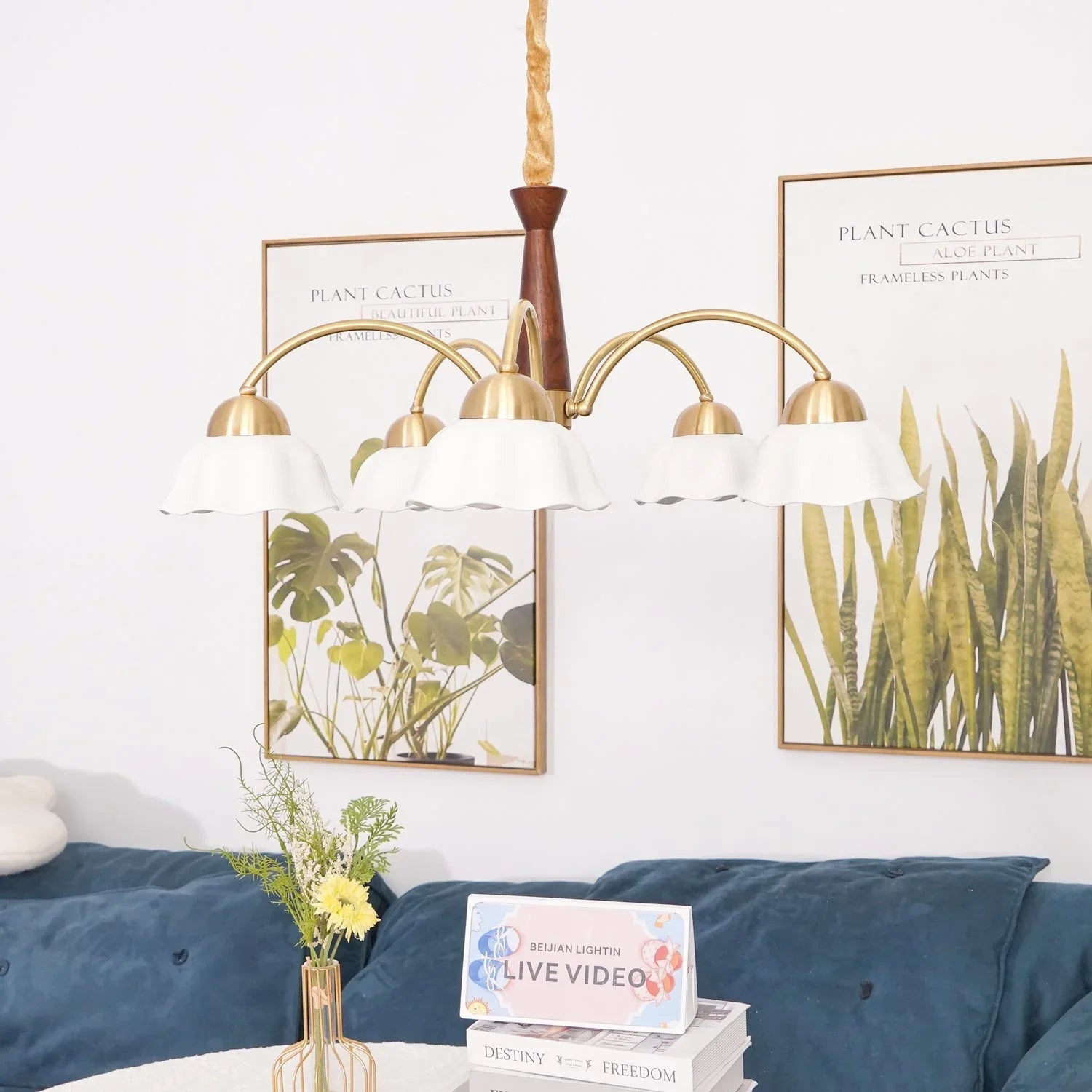Modern brass chandelier with five white lampshades over a living room table and blue sofa