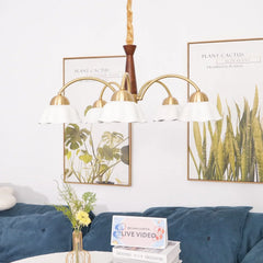 Modern brass chandelier with five white lampshades over a living room table and blue sofa