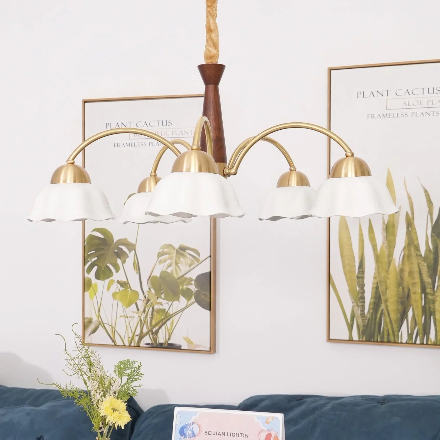 Swedish modern 3-head chandelier with brass arms, white petal-shaped shades, and walnut wood accent above blue sofa