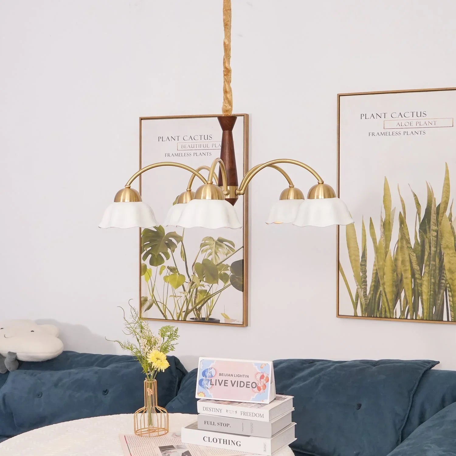 Swedish modern brass chandelier with 3 white flower-shaped pendant lamps over a cozy living room table