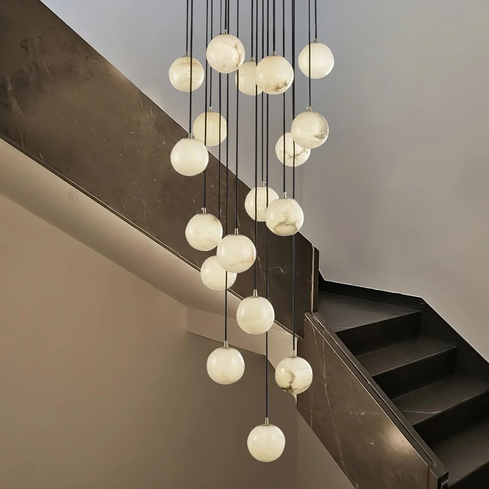 Modern cluster chandelier with 19 alabaster globe lights hanging in a staircase with dark steps