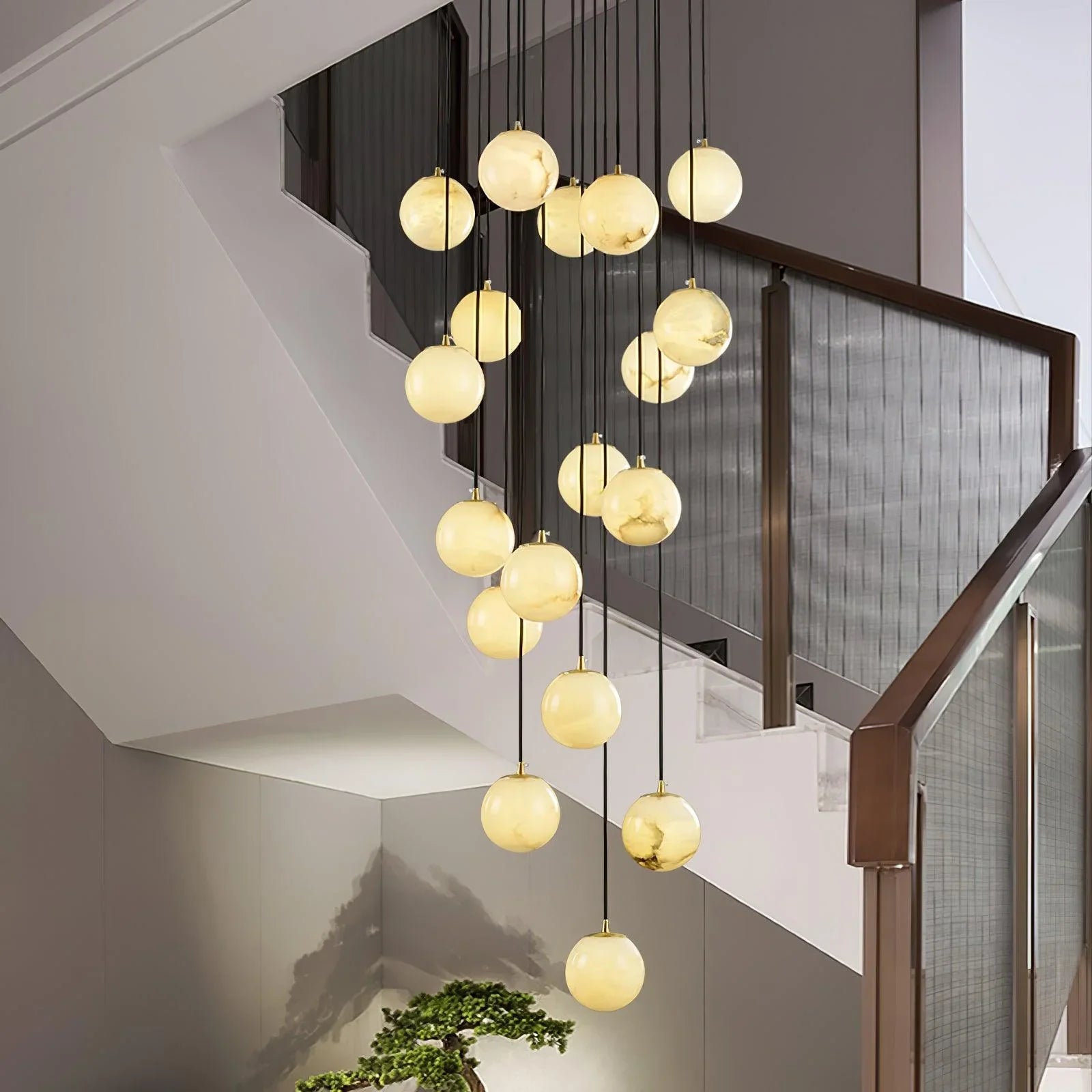 Modern cluster chandelier with alabaster ball pendants hanging in a staircase with gray walls and glass railing