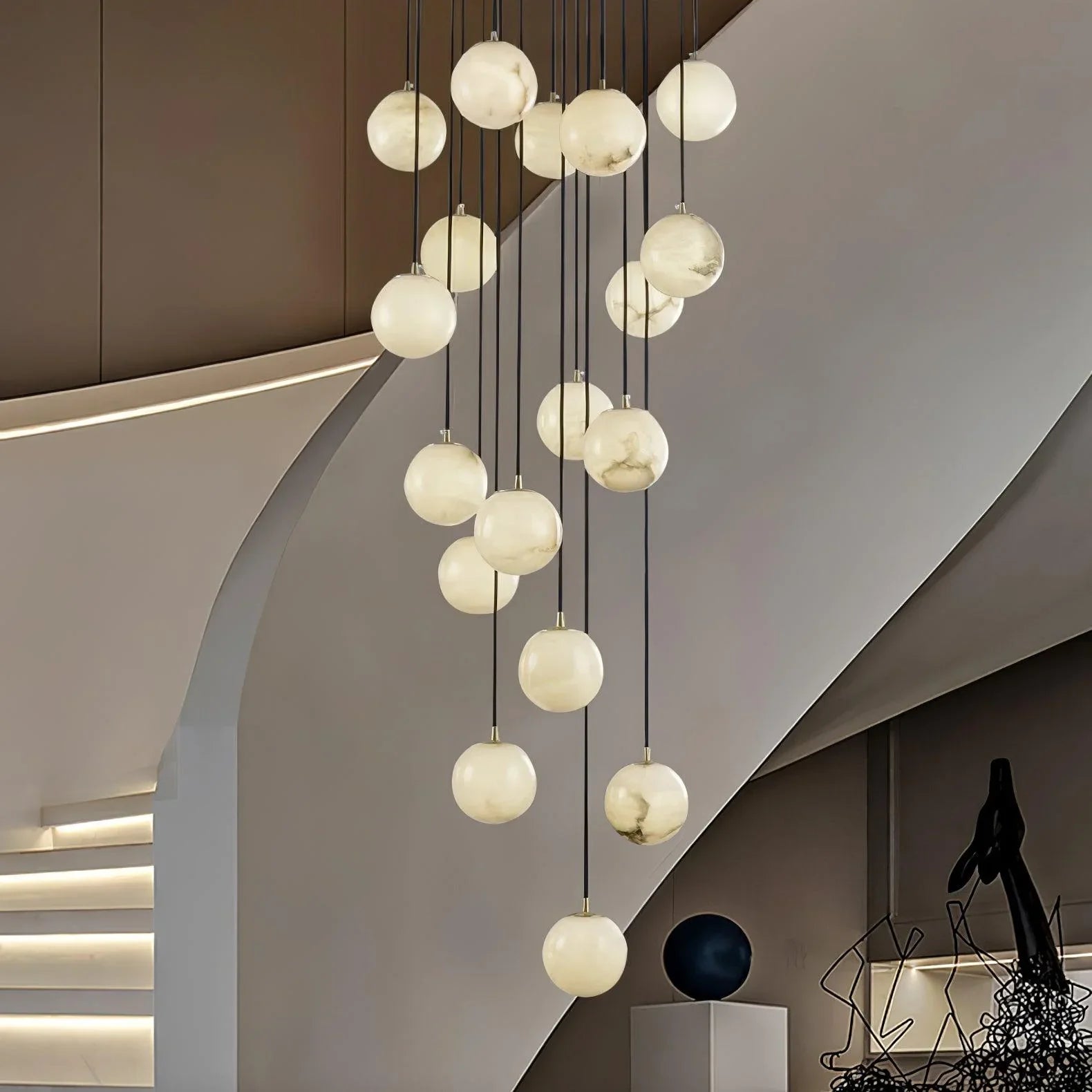 Modern cluster chandelier with alabaster globe pendant lights hanging in a stylish curved staircase interior