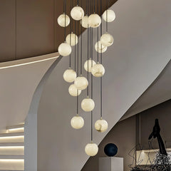 Modern cluster chandelier with alabaster globe pendant lights hanging in a stylish curved staircase interior