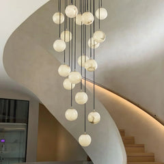 Modern cluster chandelier with alabaster globe pendants hanging in a minimalist curved staircase interior