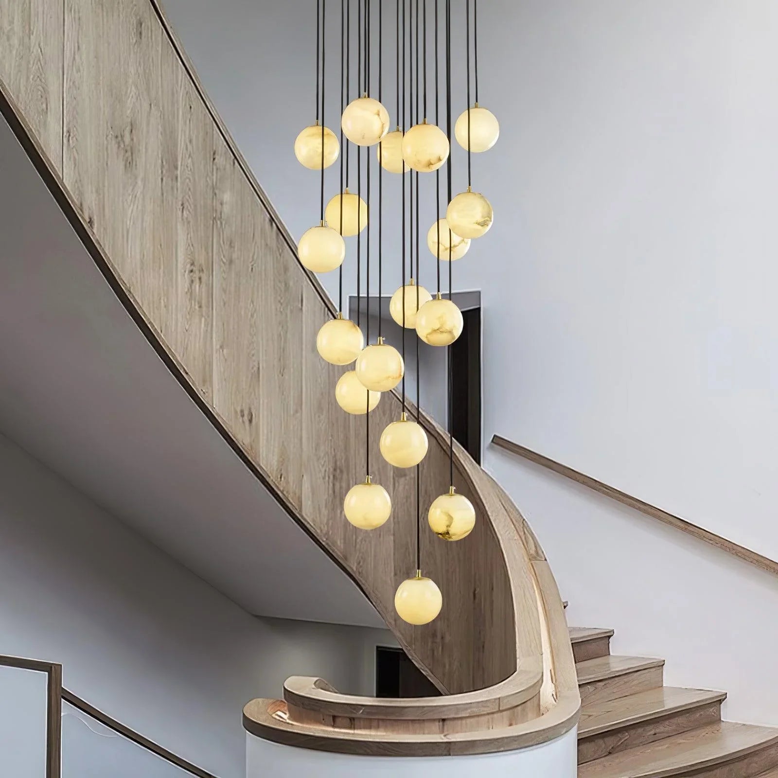 Modern chandelier with alabaster ball pendants hanging in wooden curved staircase interior
