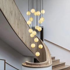 Modern chandelier with alabaster ball pendants hanging in wooden curved staircase interior