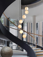 Modern chandelier with six alabaster globe pendants hanging in a stylish spiral staircase space