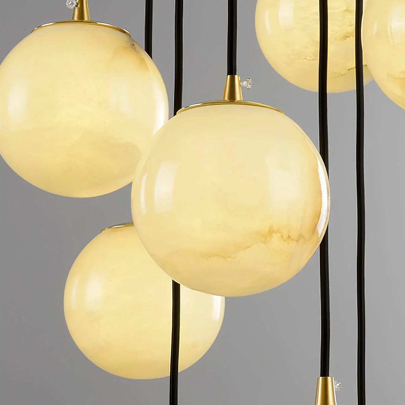 Modern cluster chandelier with alabaster ball pendants and black cords, warm ambient lighting