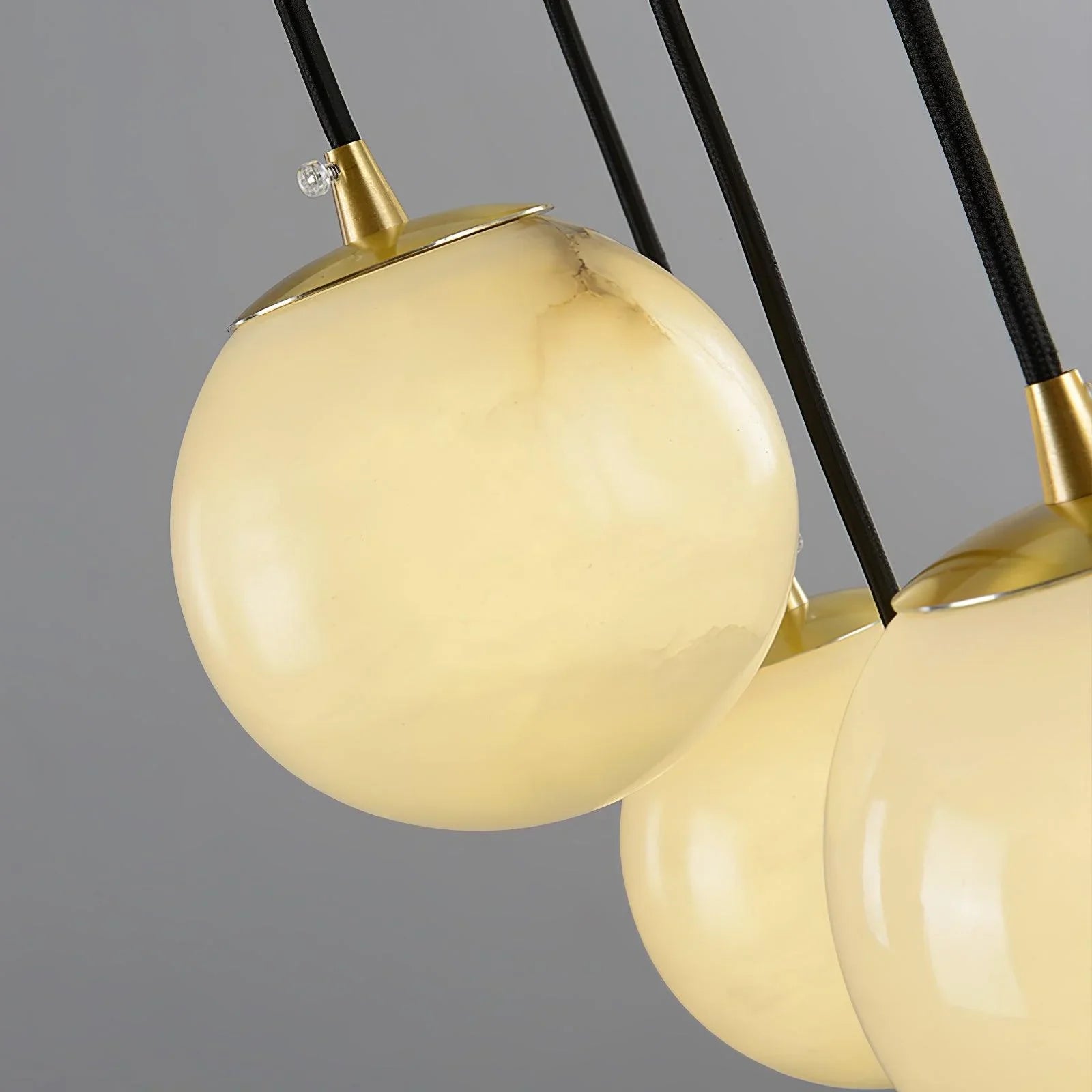 Close-up of modern pendant chandelier with three alabaster glass globes and brass fixtures by YH Lamps