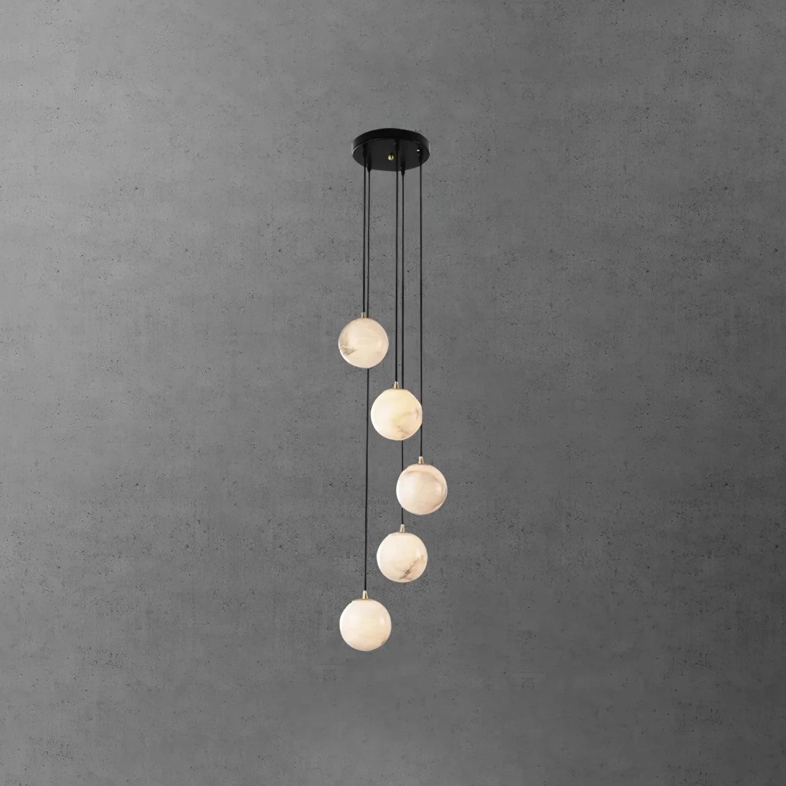 Modern chandelier with five alabaster globe pendant lights hanging from a black round canopy on a gray textured wall