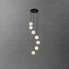 Modern black pendant chandelier with seven alabaster glass globes hanging at varying lengths against gray wall