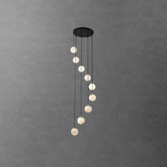 Modern pendant chandelier with nine alabaster ball lights hanging from a round black canopy on gray concrete wall