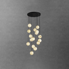 Modern chandelier with multiple alabaster globe pendant lights hanging from black round canopy against gray concrete wall