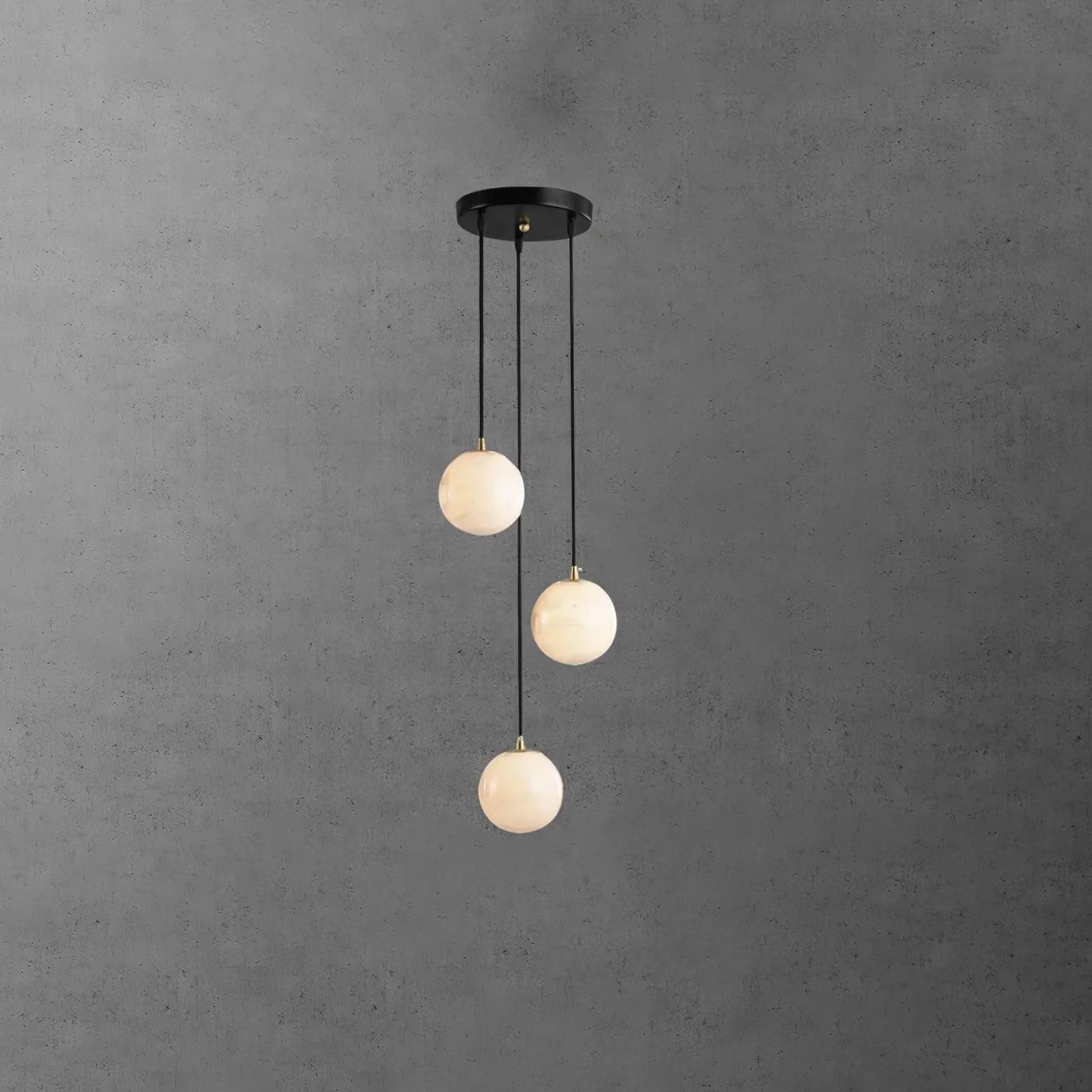 Modern pendant chandelier with three alabaster globe lights and black round ceiling canopy on gray wall