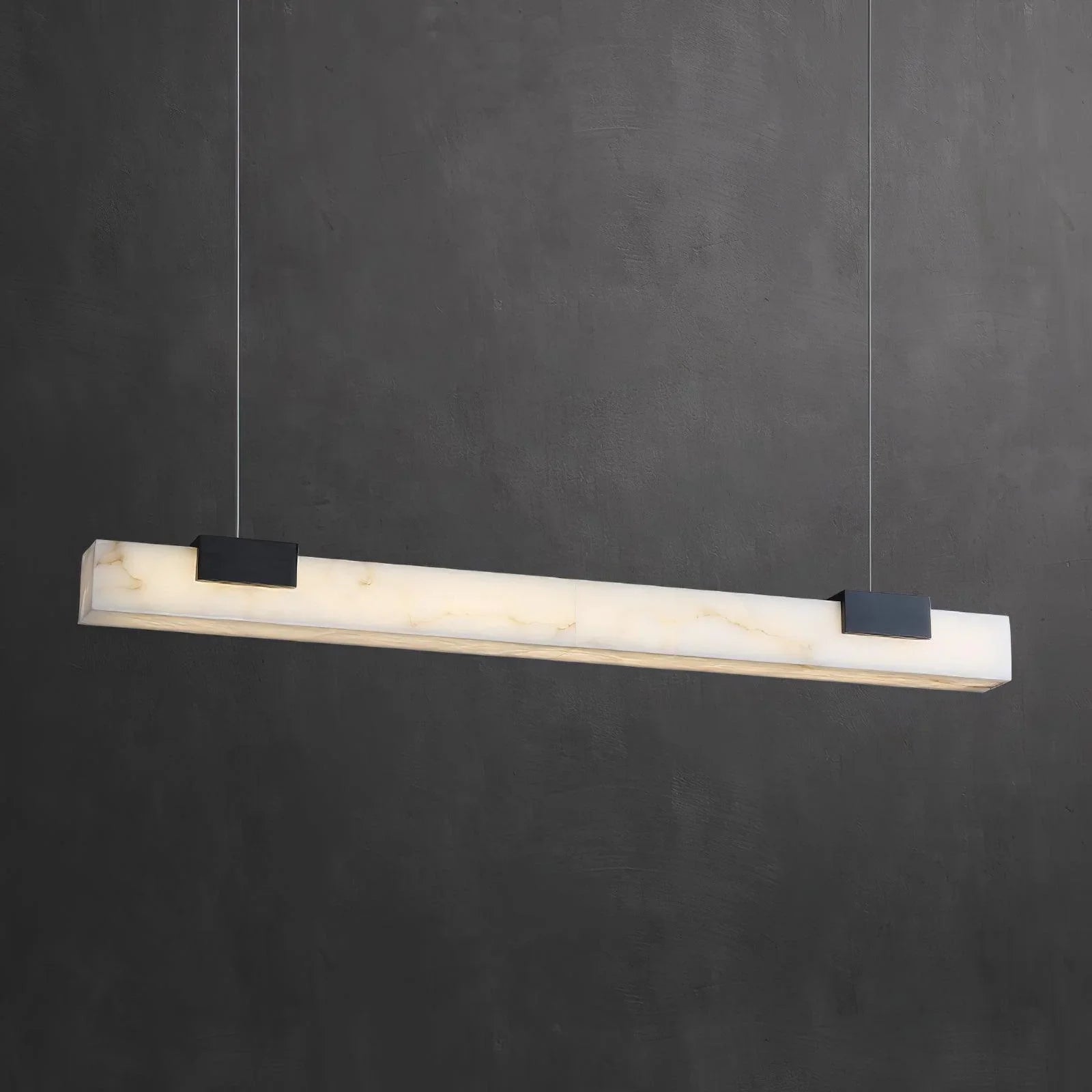 Modern rectangular alabaster pendant lamp with warm light, black ceiling mounts, against dark gray wall
