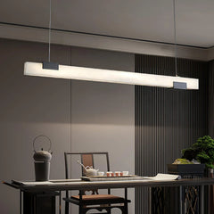 Modern minimalist black and white elongated pendant lamp over dining table with teapot set and greenery