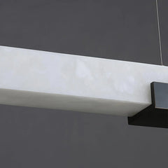 Modern rectangular alabaster pendant light with black metal accents hanging against gray background