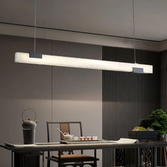 Modern linear alabaster pendant lamp with warm light hanging above a dining table with tea set and decorative plants