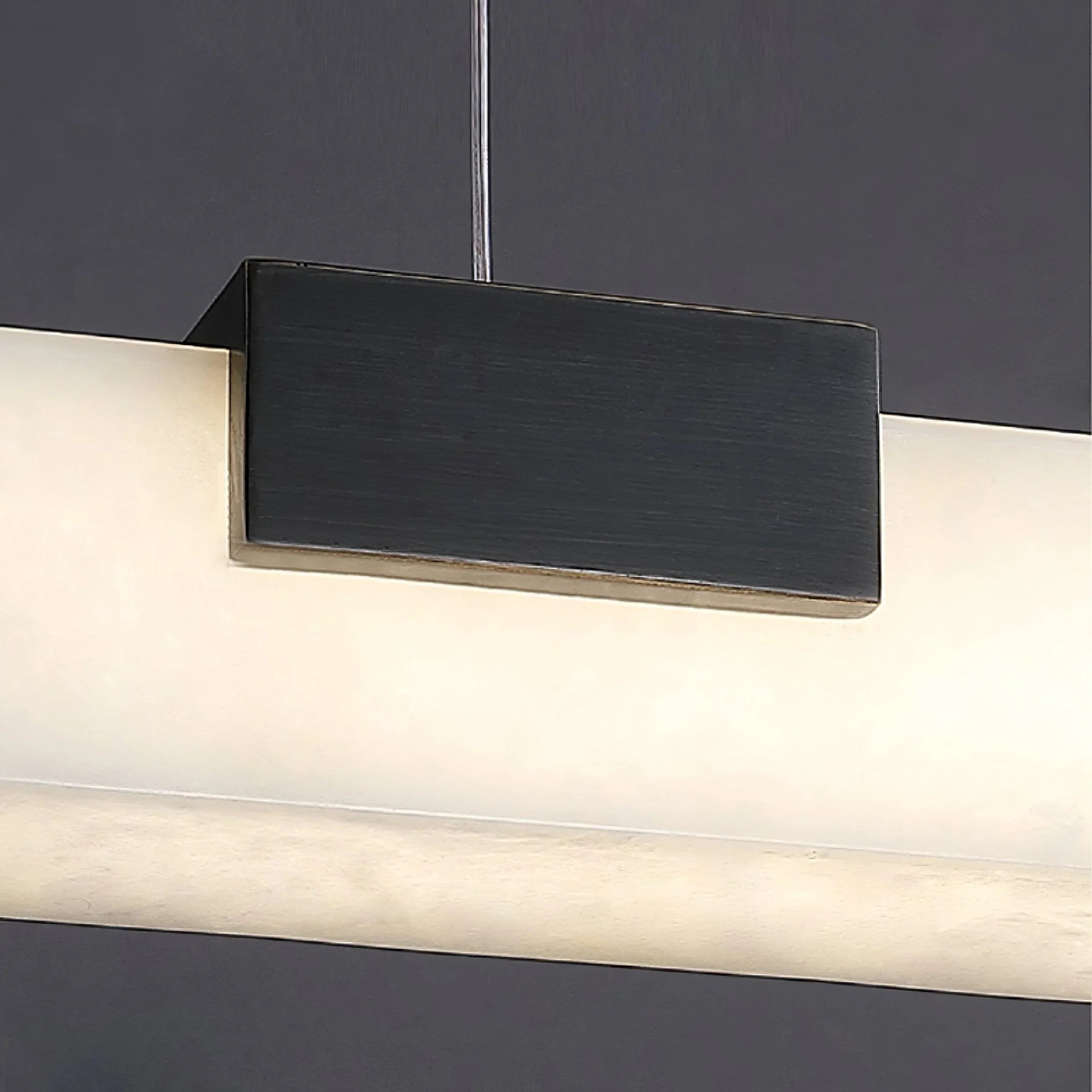 Modern pendant lamp with black metal mount and alabaster white shade emitting warm light