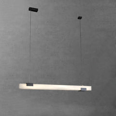 Modern linear pendant lamp with alabaster shade and black metal accents hanging against gray wall