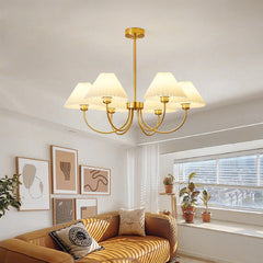 Modern brass and white 4-head chandelier over a cozy living room with wall art and sofa