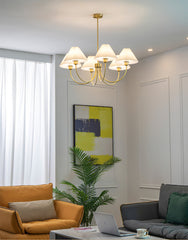 Modern brass pendant chandelier with four white pleated shades in a stylish living room