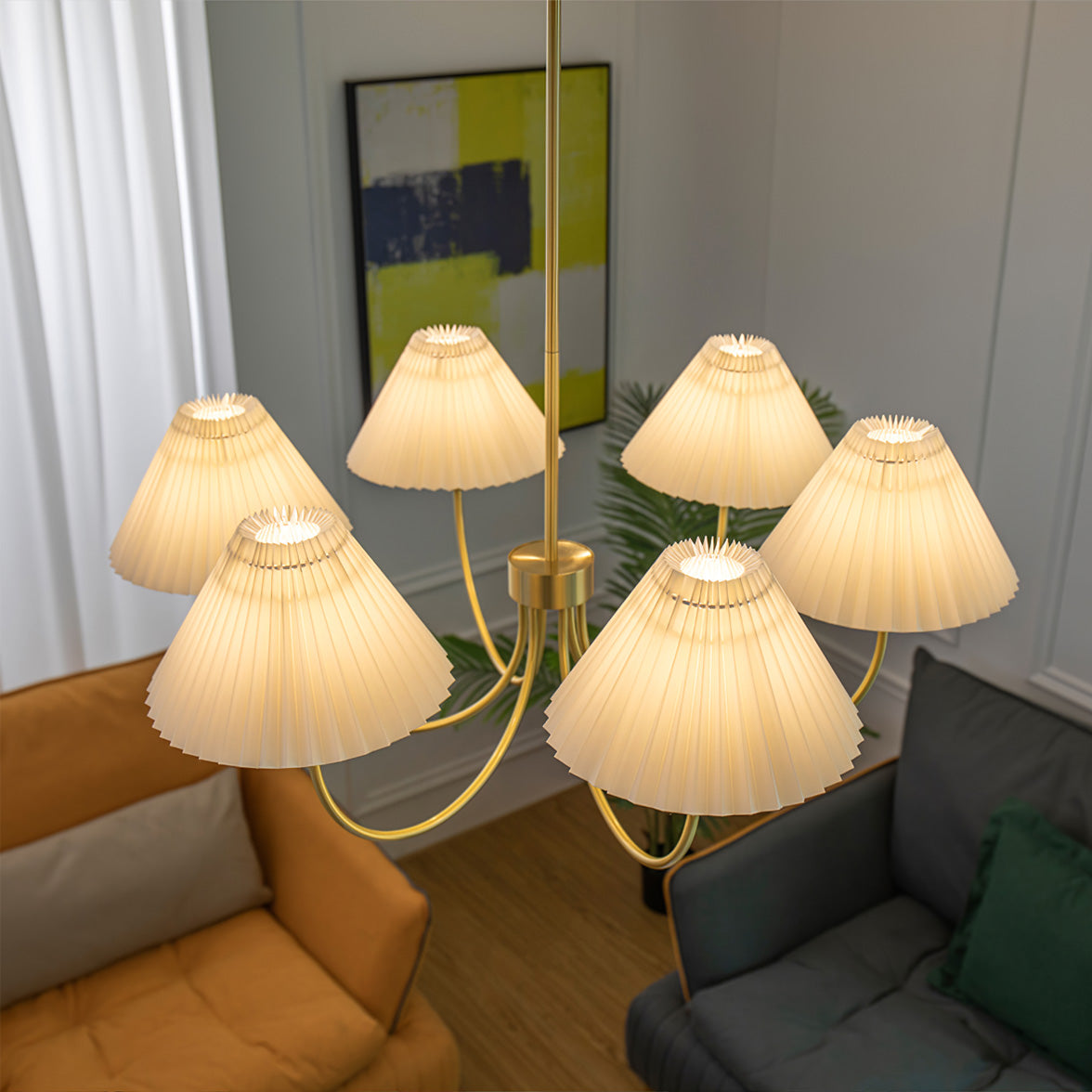 Modern brass chandelier with six pleated white shades, hanging over a stylish living room