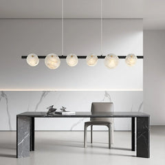 Modern dining room with black marble table, gray chair, and linear pendant chandelier with six round white glass lights