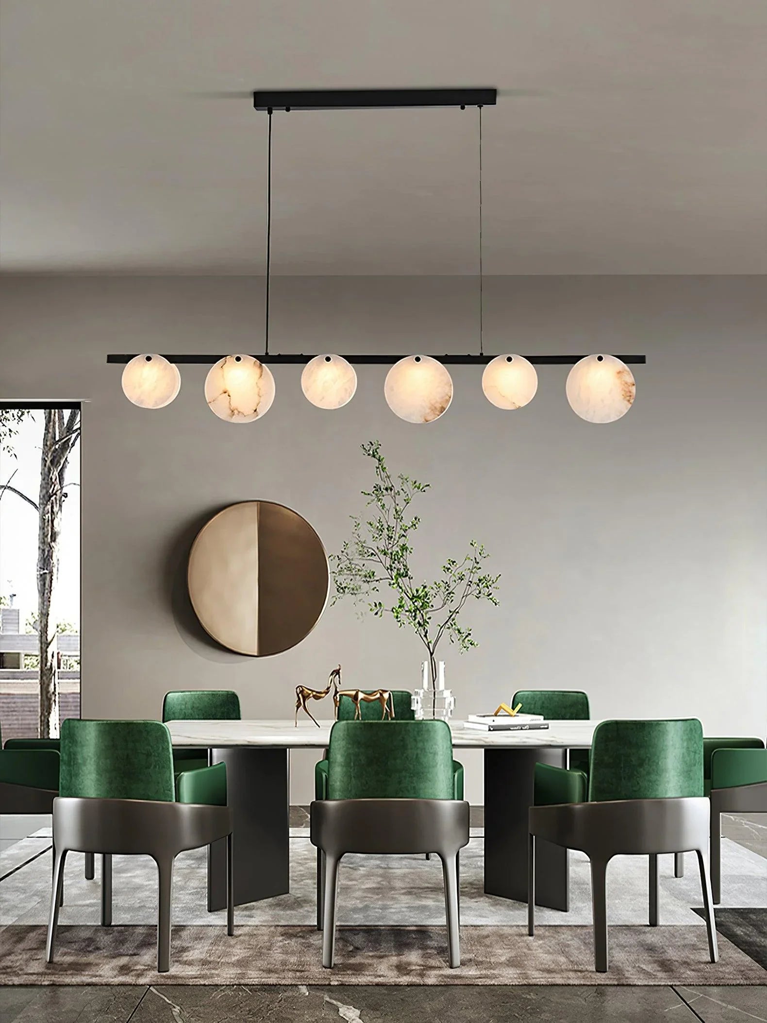Modern dining room with green velvet chairs, marble table, brass chandelier with six round alabaster lampshades
