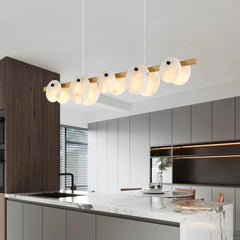 Modern dining room chandelier with five white glass heads and brass accents above marble kitchen island