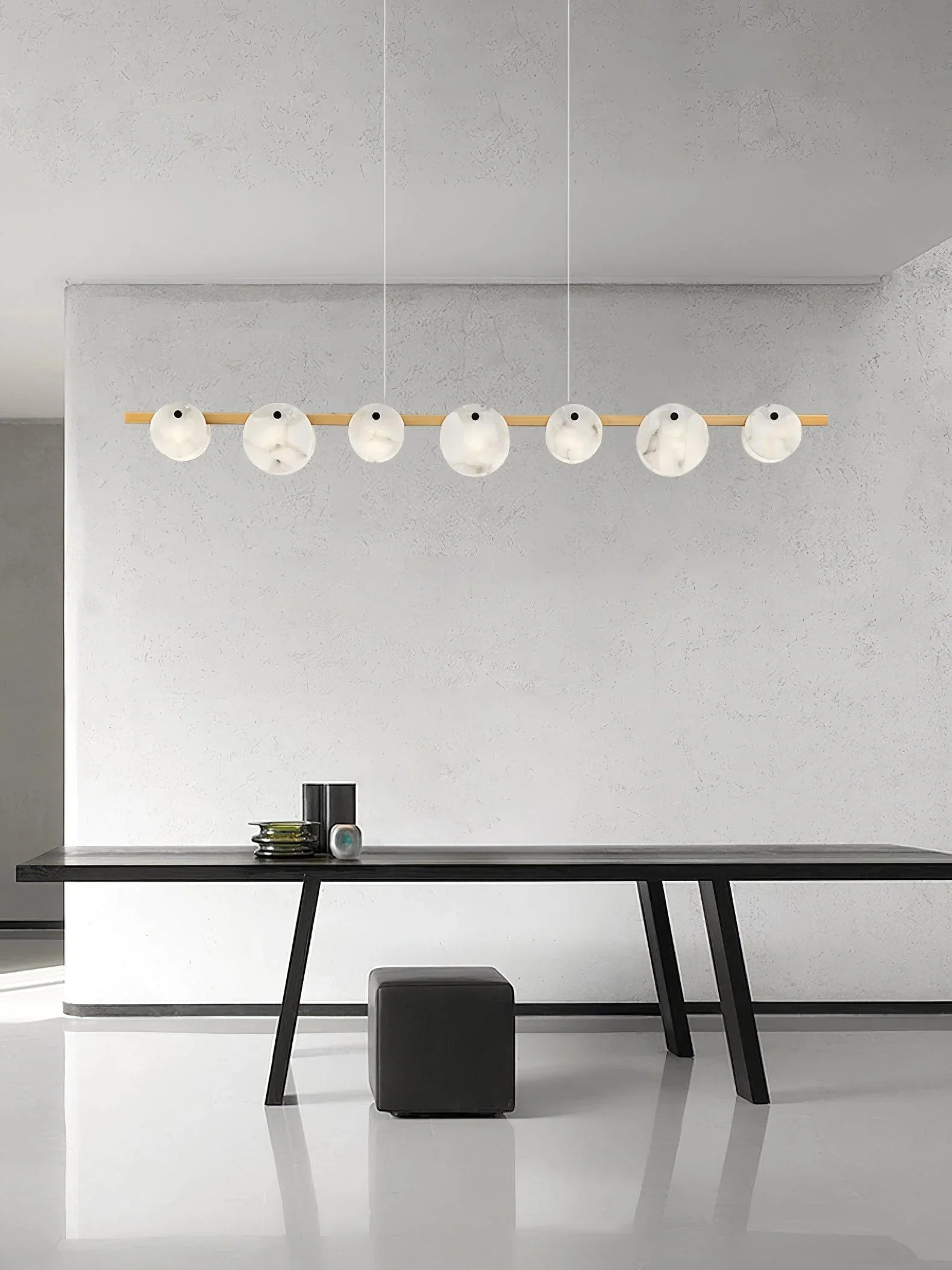 Modern dining room with black table, black pouf, and YH Lamps brass pendant chandelier with 7 round white marble lights