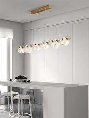 Modern dining room with a brass and white pendant chandelier featuring circular shades over a gray island with white stools