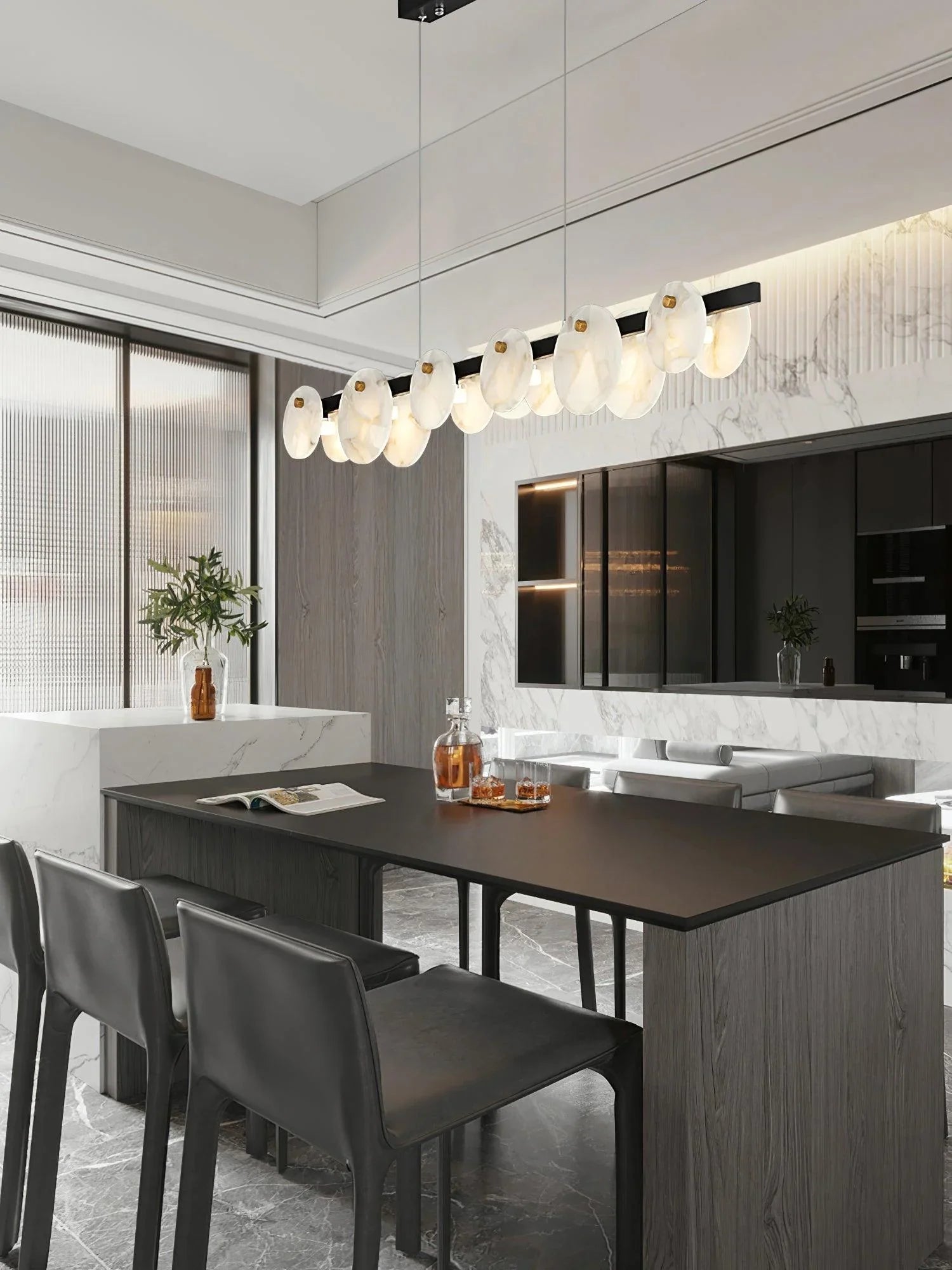Modern dining room with black table, dark chairs, marble accents, and a long pendant chandelier with white glass discs