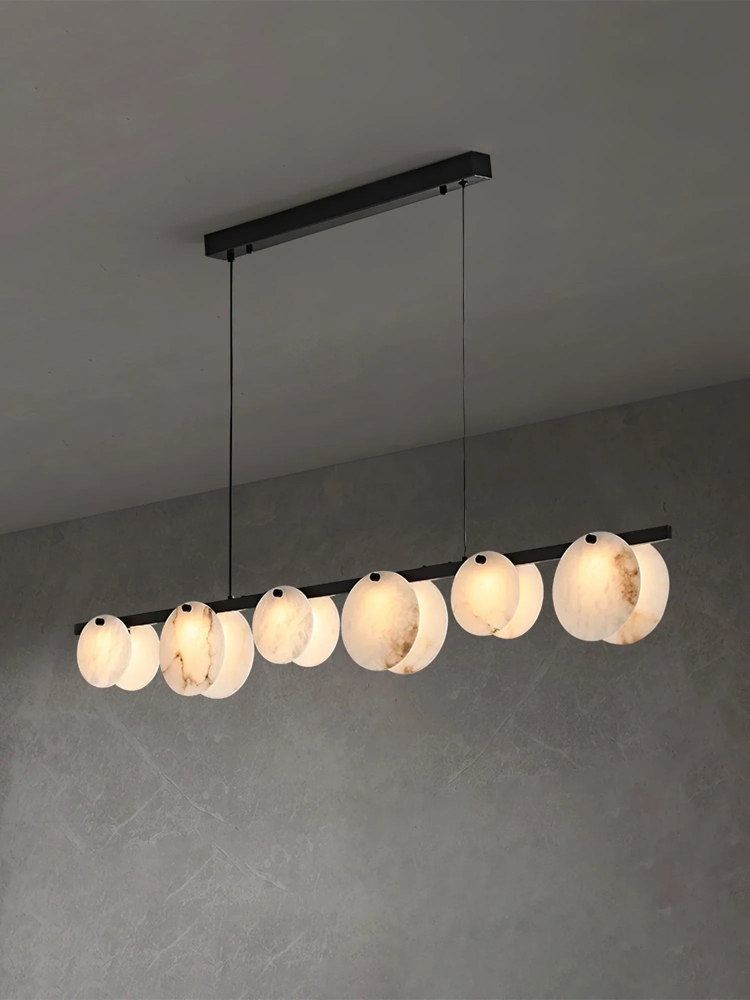 Modern linear pendant chandelier with round alabaster lampshades suspended from black ceiling mount