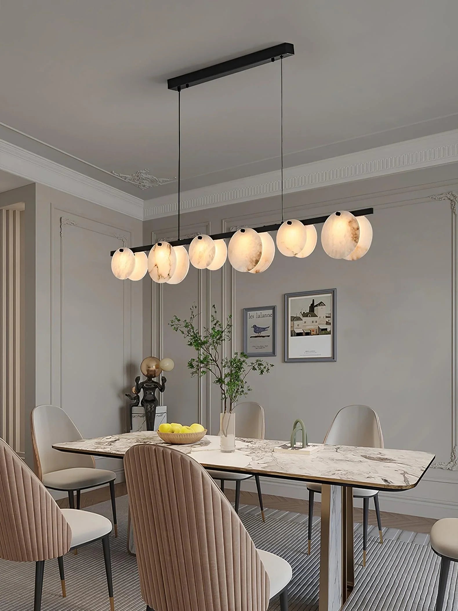 Modern dining room with marble table, beige velvet chairs, and brass 5-light pendant chandelier