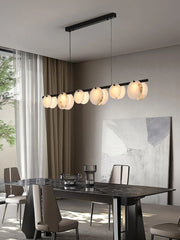 Modern dining room with black marble table, leather chairs, and round pendant chandelier with warm light