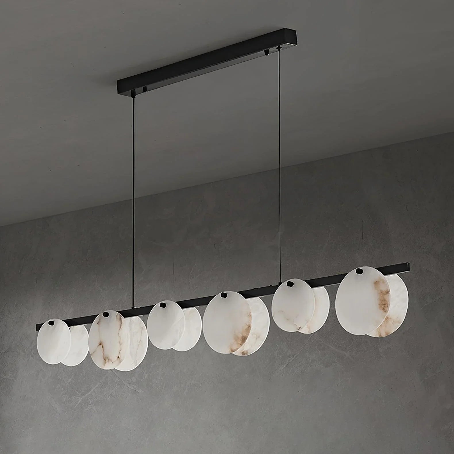 Modern pendant chandelier with white marble textured circular shades, suspended on black metal bars in a minimalist room