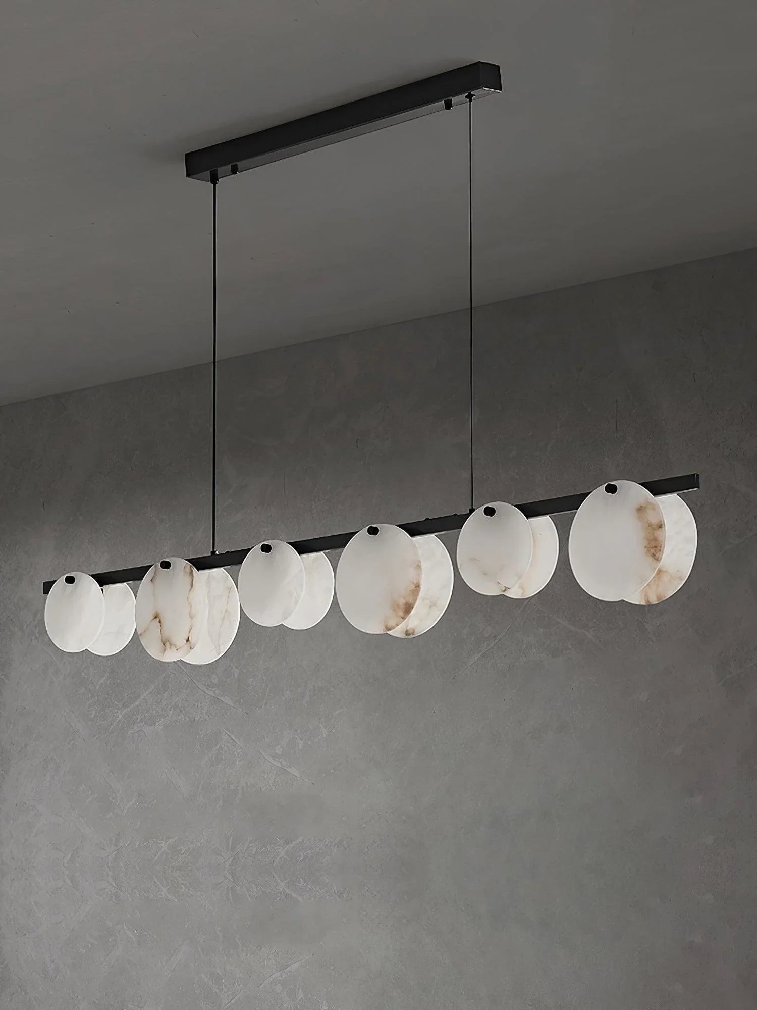Modern pendant chandelier with eleven marble-textured white circular shades on a black bar, hanging in gray room