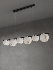 Modern pendant chandelier with eleven marble-textured white circular shades on a black bar, hanging in gray room
