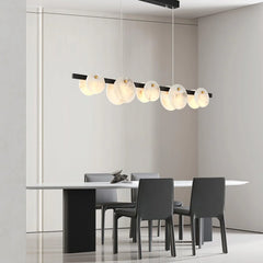 Modern dining room with black chairs, white table, and sleek linear pendant chandelier with alabaster shades