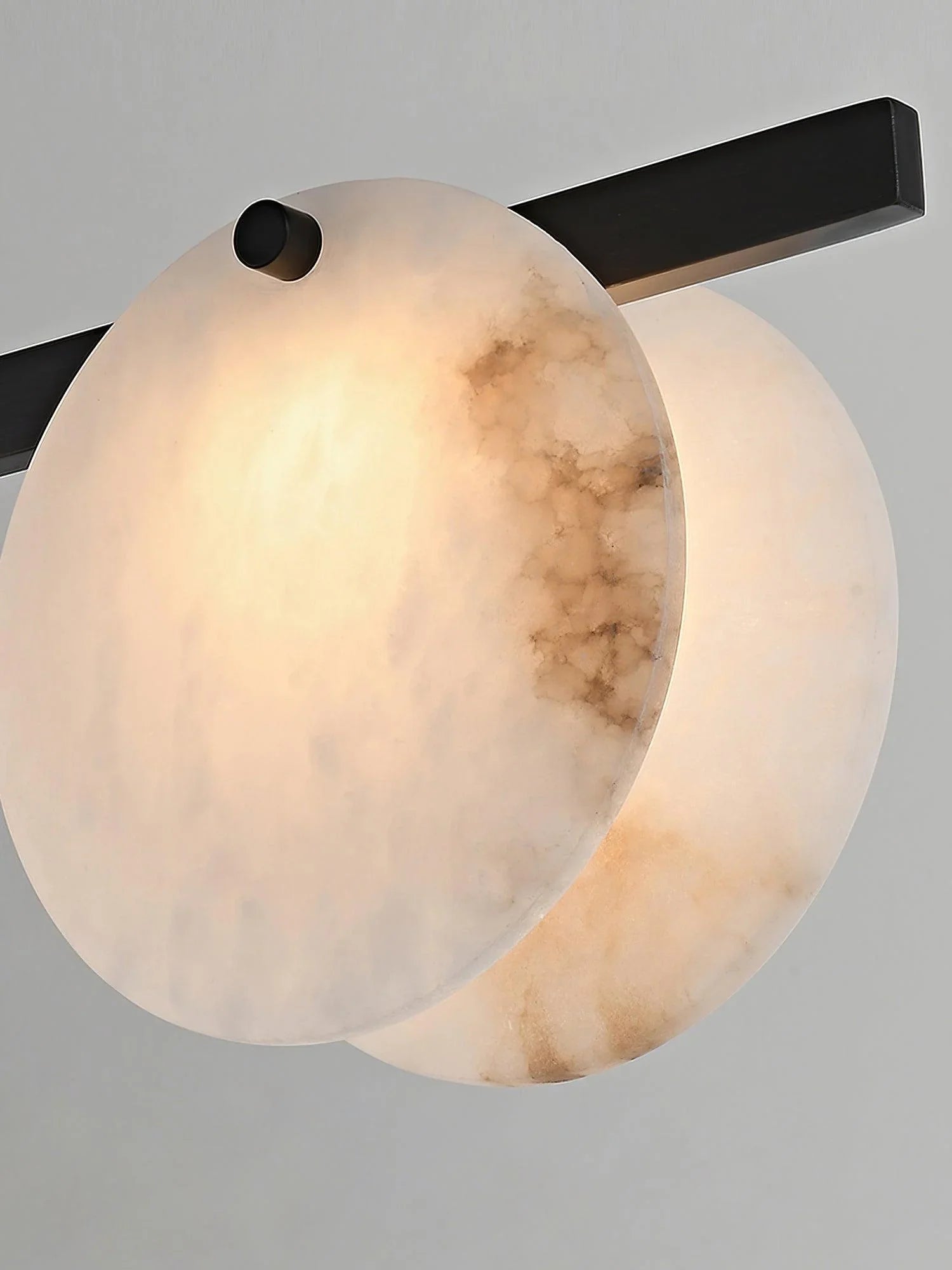 Modern wall sconce with two round alabaster stone lamps and black metal fixture