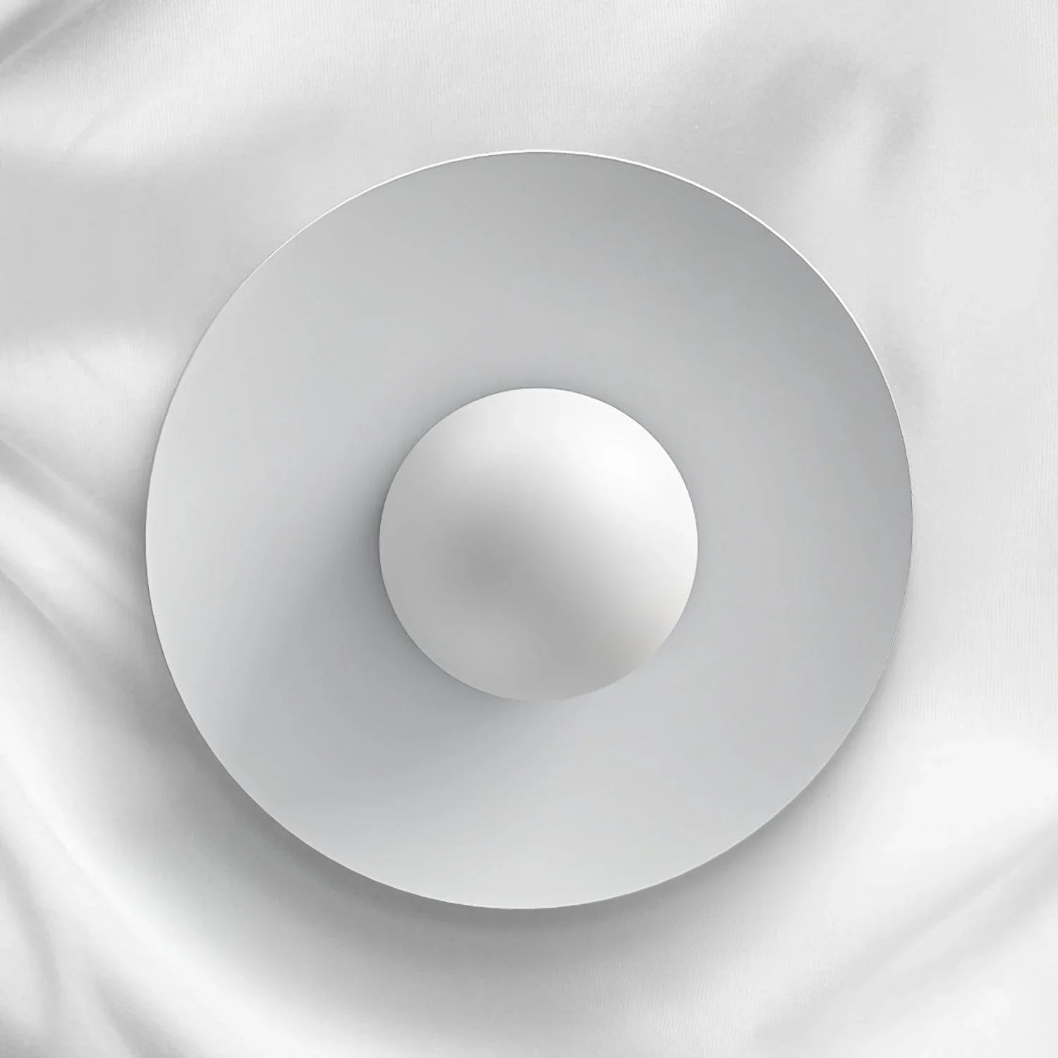 Modern white circular pendant lamp with smooth layered design against white fabric background